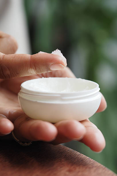 istock Hand applying petroleum jelly from white container in indoor setting 2229604531