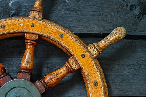Rustic wooden ship wheel against dark wall