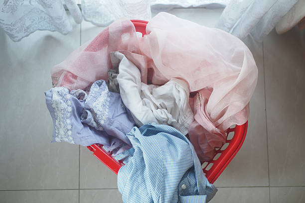 istock Laundry basket filled with colorful clothes on tiled floor 2229605896