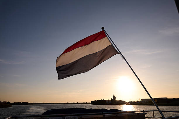 Yemeni flag waving on a boat sailing on a river at sunset