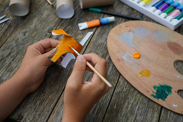 istock DIY and kid's creativity. Step by step instruction: how to make tiger from toilet roll tube. Step four, cover the entire roll with orange paint. 2229609820