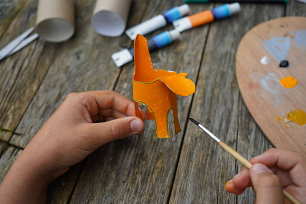 istock DIY and kid's creativity. Step by step instruction: how to make tiger from toilet roll tube. Step four, cover the entire roll with orange paint. 2229609848
