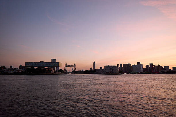 Rotterdam cityscape reflecting on the nieuwe maas during a colorful sunset