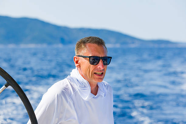 Crew member enjoying sailing in sailboat cockpit.