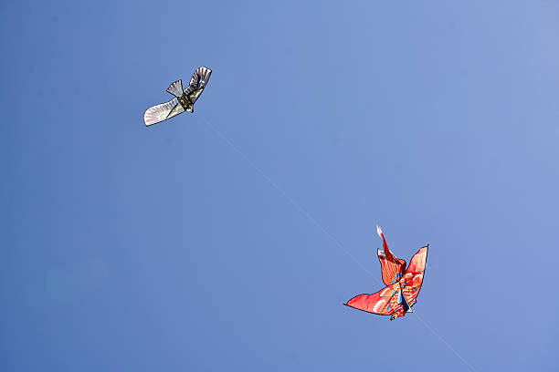 Two colorful kites soaring high against a clear blue sky, showcasing vibrant designs and freedom in the open air.