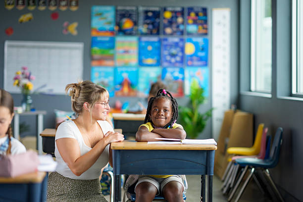 istock Smiling Student and Caring Teacher Interacting in a Colorful Classroom Environment 2229618448