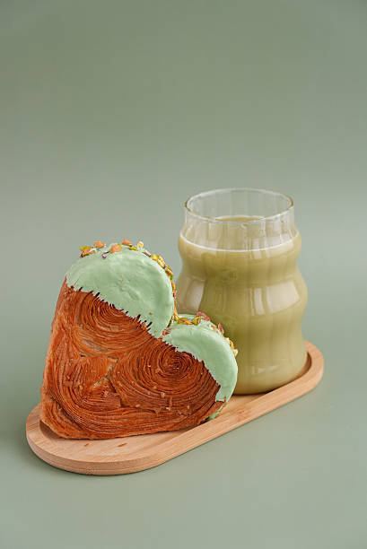 Nutrient-rich matcha drink with Green latte Matcha tea coffee with Delightful and vibrant heartshaped pastry croissant treat, beautifully topped with colorful frosting nut galore. Mock up template copy space. Food experimentation viral dessert creative
