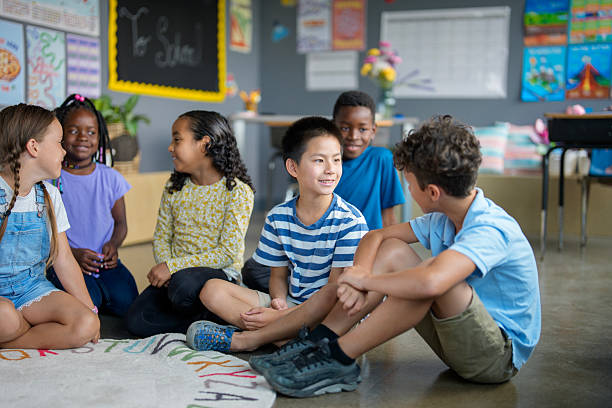 Children of various ethnic backgrounds sitting together on a classroom floor, engaging joyfully and expressing a sense of community, illustrating friendship and collaboration among young learners in an educational environment.