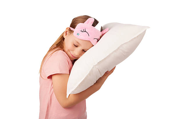 istock Smiling girl wearing sleeping mask hugging pillow on white background 2229619469