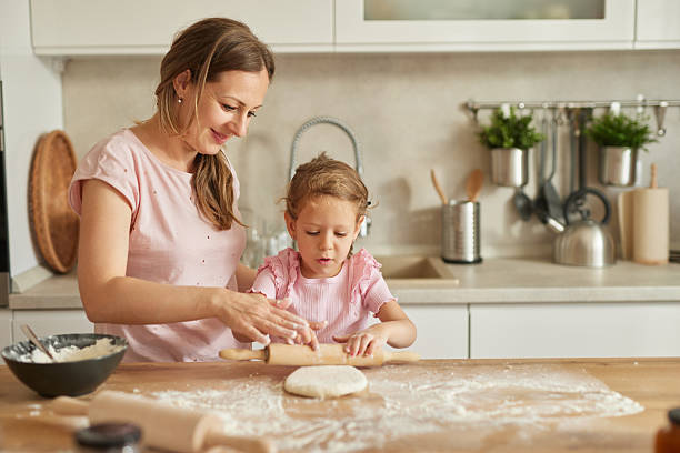 istock Mother and daughter happily preparing dough in kitchen 2229619648