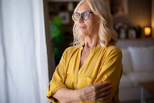 istock Senior woman looking through window while contemplating life at home 2229619682