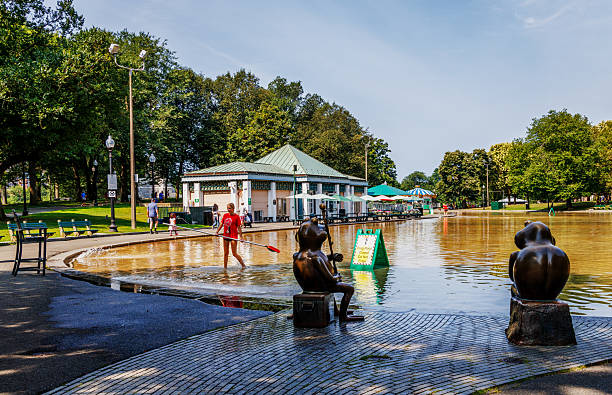 Boston, Massachusetts, USA - August 10, 2025: The Frog Pond and Pavilion with the pond full of water, but closed for maintenance. The Boston Common Frog Pond sits at the heart of Boston Common. Managed by The Skating Club of Boston in partnership with the City of Boston, Frog Pond is home to a winter ice skating rink and learn-to-skate school, a reflecting pool in the spring and fall, and a summer spray pool.