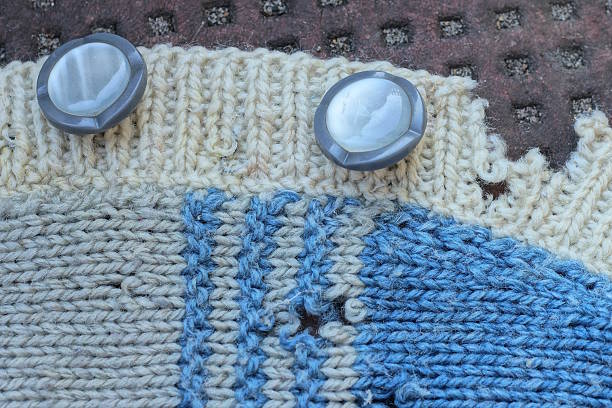 istock two big plastic buttons on wool torn gray blue fabric sweater 2229626639