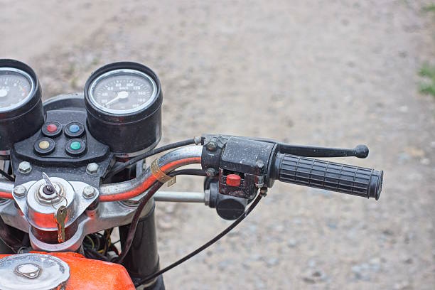 part of one old motorcycle from steering wheel and speedometer on the background of gray road on city street
