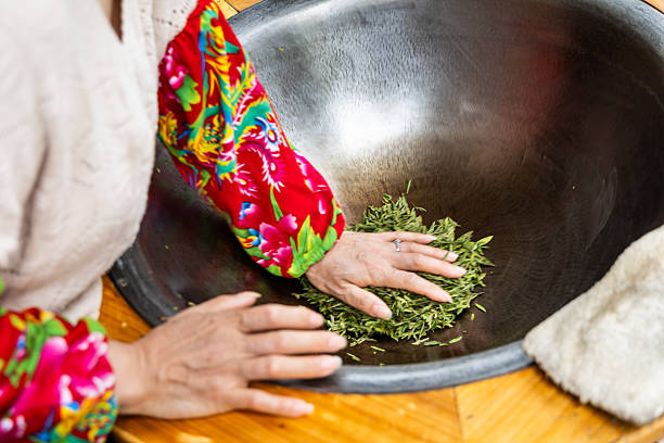 Working pressing the longjing tea leaves in a pan to flatten the leaves as second step in pan-fry process