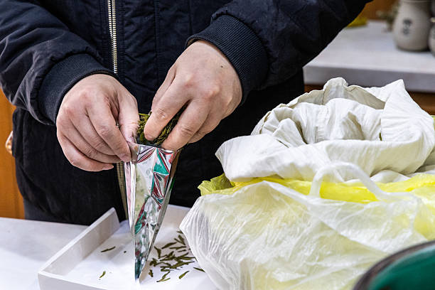 Worker packing processed longjing tea leaves into aluminium bag for sale