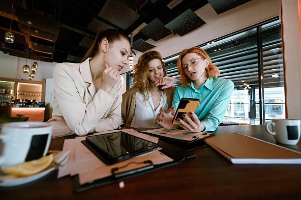 istock Businesswomen collaborating on a project at a modern cafe while discussing ideas and reviewing documents during a sunny afternoon 2229628972