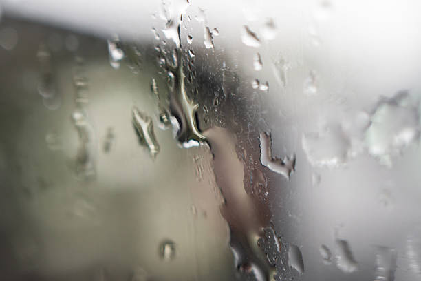 Atmospheric image depicting handprints on a misty, rainy window at night. Beyond the window we can see the defocused lights of the city traffic.