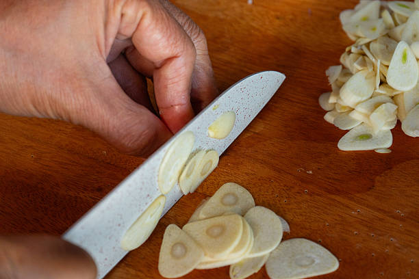 istock Indonesian woman hand slicing garlics on solid wooden cutting board 2229631755