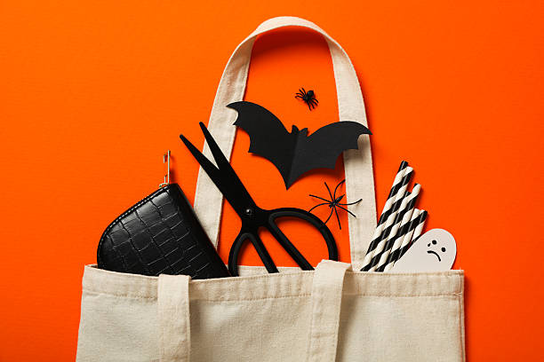 istock Scissors, case, paper ghost and bat in cotton bag on orange background, top view 2229641895