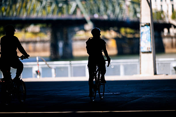 Unrecognizable people in silhouette riding bikes in the city. Shot in Downtown Portland Oregon, Pacific Northwest.