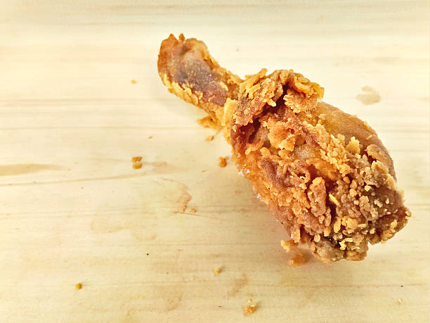 A close-up shot of a golden, crispy fried chicken leg on a rustic wooden surface, perfect for fast food and comfort food illustrations.