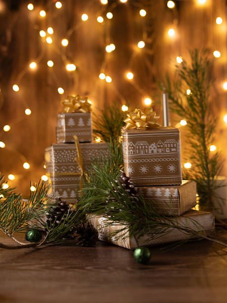 istock cozy holiday scene with festive gift boxes adorned with golden bows and pine greenery, set against warm glowing string lights on a wooden background, art, peaceful, decoration, joy, homely, texture 2229649383