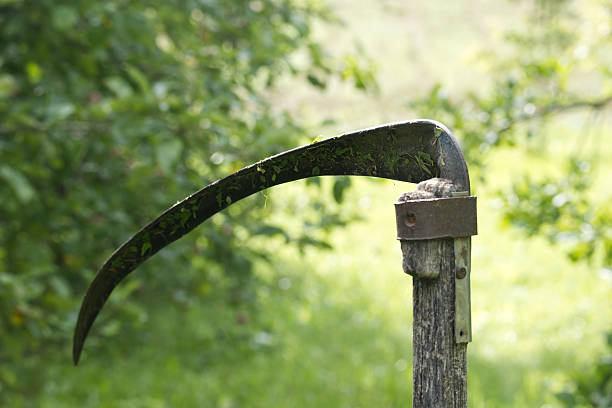 In hand scythe raised to the top of the sky against the background of clouds