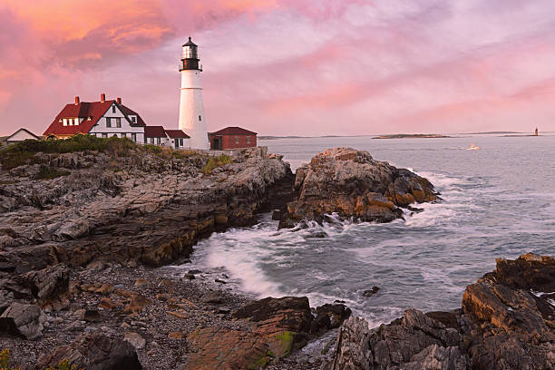 Portland Head Light at sunset surrounded by with dramatic waves and cliffs, Maine, USA