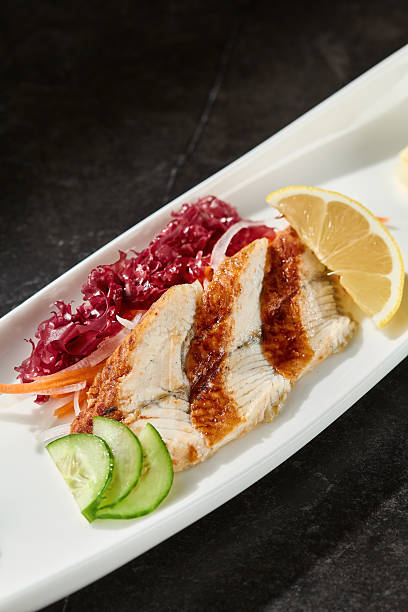 Unagi sashimi with lemon wedges, moody lighting, angled closeup composition