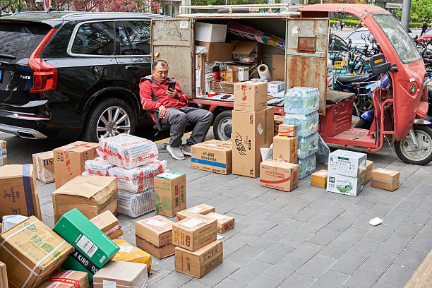 Delivery worker sorting packages on a street sidewalk in downtown Beijing, China on 19 April 2024