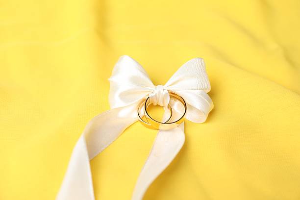 Wedding rings tied with ribbon on yellow cloth