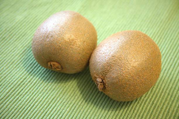 istock Two Whole Kiwis on Green Background - Close-Up with Copy Space 2229665767