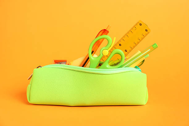 Different stationery in pencil case on orange background