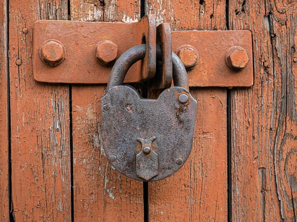 istock Old rusty padlock locks light brown wooden gate with peeling paint close-up 2229667993