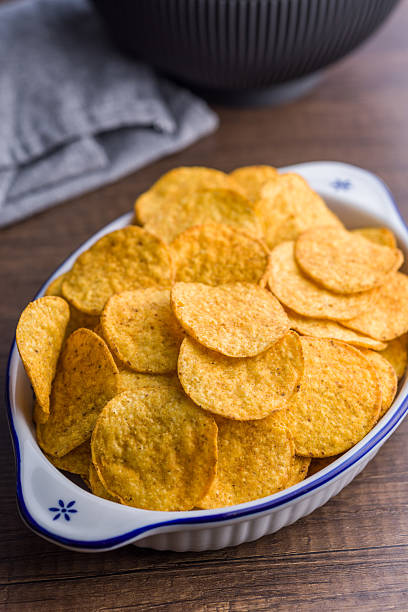 istock Crispy potato chips in bowl on wooden table. 2229670533
