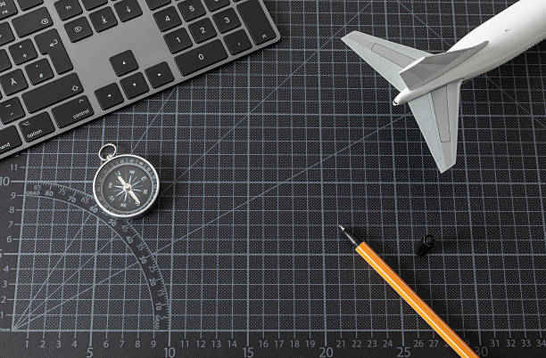 Computer keyboard on a black cutting mat, as well as vertical stabilizers and elevators of a model passenger aircraft
