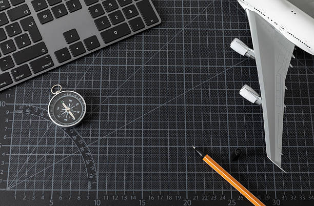 Computer keyboard on a black cutting mat, as well as the wing and engines of a model passenger aircraft