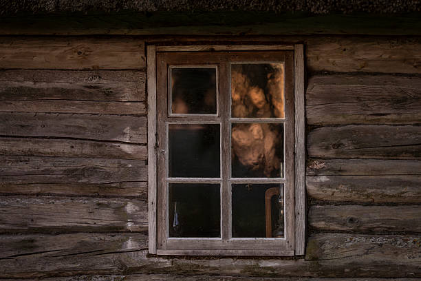 Rustic Log cabin and window with a reflection of sunrise. Old wooden log house window background.