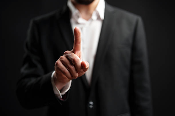 istock Man dressed in formal attire gestures with raised finger indicating a point during a discussion or presentation 2229672879