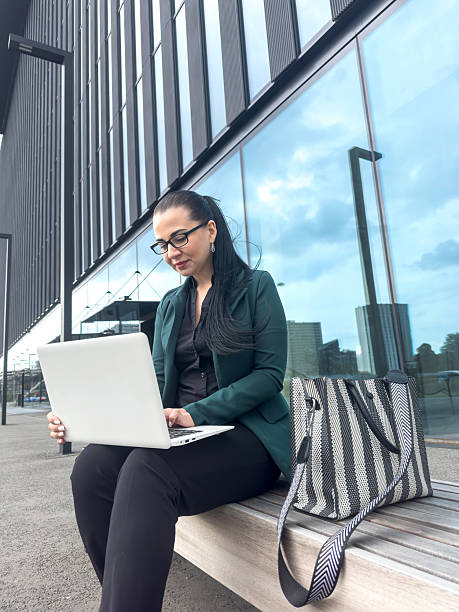 istock Successful business lady boss sitting on bench using laptop computer outside modern glass cityscape 2229676360