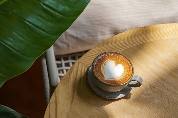 latte coffee art on wooden plate at desk in sun shine with shade of the tree