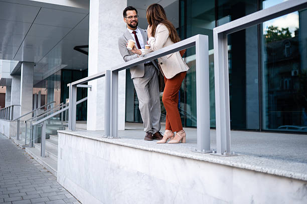 istock Business partners drinking coffee and discussing during break outside office building 2229679071
