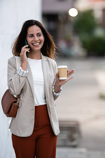 istock Businesswoman walking and talking on phone while holding coffee 2229679114