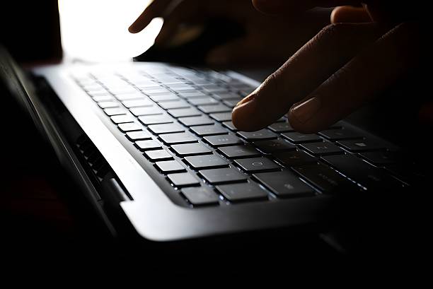 istock A person's hands are seen typing on a laptop keyboard in a low-light setting. The backlit keys are clearly visible. 2229679236