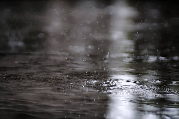 istock raining on the concrete walk way full with rain droplets splash ring bounce off the surface of water with reflected of white cloudy sky 2229679430