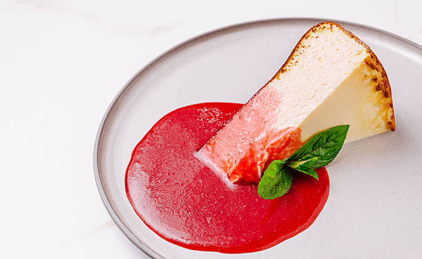 istock Delicious slice of cheesecake with raspberry sauce and mint garnish on a plate 2229682723