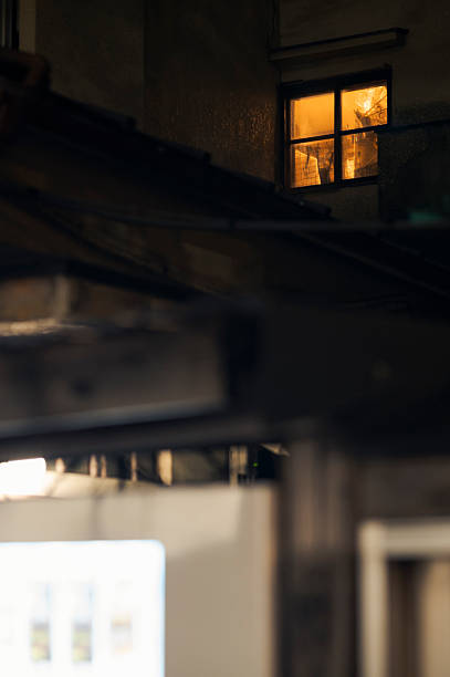 istock Warm window light glowing in dark urban alley 2229682789