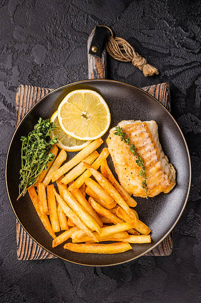 istock Homemade Fish and chips with roast cod whitefish fillet and fried potatoes on plate. black background. top view 2229683274