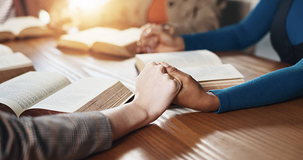 istock Hand holding, Bible and people with prayer for religion, guidance or support with scripture for worship. Christianity, faith and group by table, book of God and praise with spiritual education 2229683353
